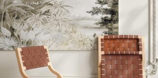 Two wooden chairs with woven brown leather seats and backs; one chair is upright and the other is folded and leaning against a wall with a nature-themed mural. The floor is light wood.